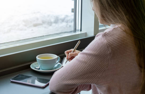 istock Woman is using pen writing Record Lecture note, Woman writing in coffee shop. 1912756255