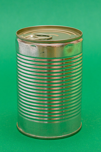 Unopened Tin Can with Blank Edge on Green Background. Canned Food. Aluminum Can for Safe and Long Term Storage of Food. Steel Sealed Food Storage Container