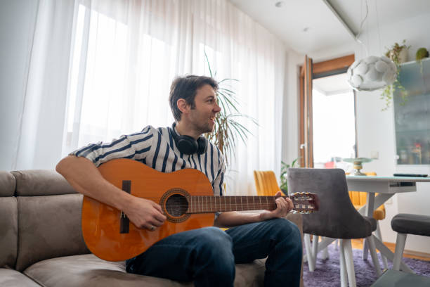 istock Man playing acoustic guitar at his apartment 1912802291