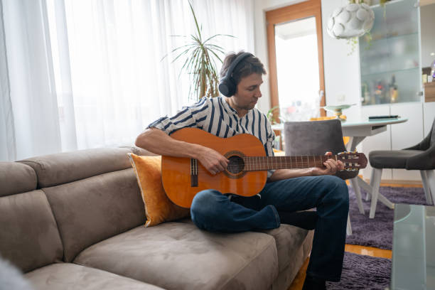 istock Man playing an acoustic guitar in a brightly lit room 1912814199