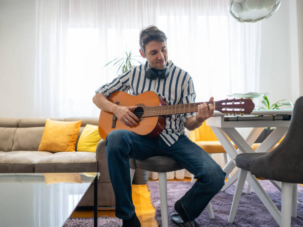 istock Man playing acoustic guitar at his apartment 1912816787