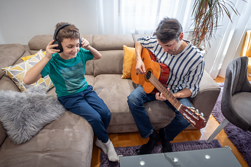 Shot of a father teaches son playing guitar
