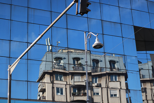 Full frame photo of modern glass wall of building with city buildings and sky reflection seen on. Shot with a full frame mirrorless camera.