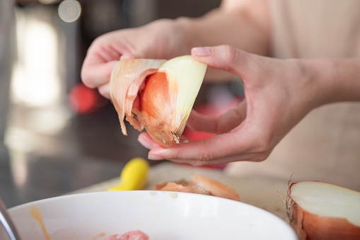 A woman's hands peel an onion into slices, close-up. The process of cooking onions as a dressing. High quality photo