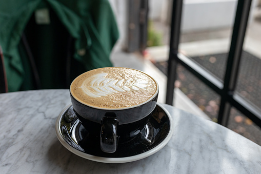 Hot coffee latte with latte art milk foam in cup mug on desk on top view.