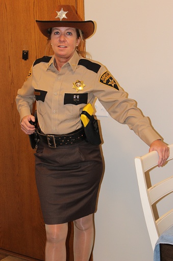 Sheriff's deputy, Mature, female, white, Blonde, in brown uniform indoors