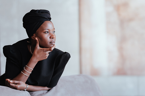 Thoughtful woman in black attire and headscarf looking away
