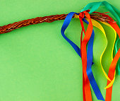 Close up of an Easter handmade whip with colorful ribbons on green background