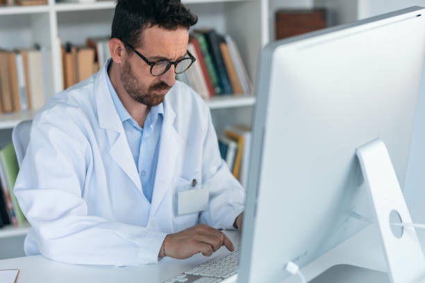 istock Mature male doctor working with computer while writing notes in the medical consultation 1913063357