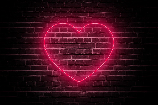 Illuminate your romance with the soft glow of a neon heart on a dark brick wall, casting a warm and intimate ambiance—a perfect visual ode to love on Valentine's Day.
