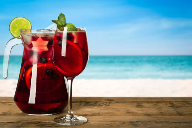 Refreshing Red Sangria on wooden table near sea, space for text