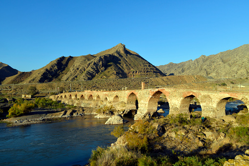 Khomarlu, Khoda Afarin County, East Azerbaijan province, Iran / Soltanly, Jabrayil District, Azerbaijan: big / south Khoda Afarin / Khudafarin Bridge, across the Aras River in the Caucasus, the border between Iran and Azerbaijan. One of two stone bridges, 800m apart, connecting the Iranian province of East Azerbaijan and the Jebrayil Rayon of Azerbaijan. The big bridge has 15 arches and was built in the 13th century, all 15 arches are intact, it may date from the pre-Islamic Achaemenid Empire (550–330 BC). Silk road.