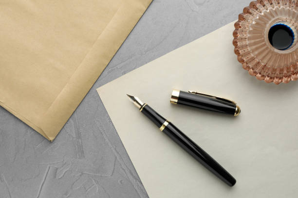 istock Stylish fountain pen, inkwell, envelope and paper on grey textured table, flat lay 1913165017