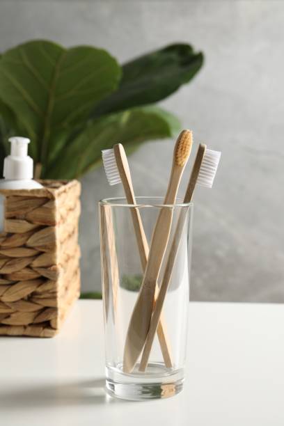 istock Bamboo toothbrushes in glass holder on white countertop 1913183860