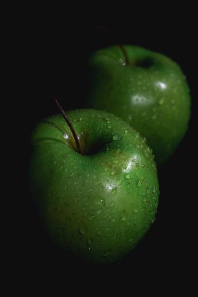 istock Apple fruit with drops of water, abstract shadow, black background 1913240287