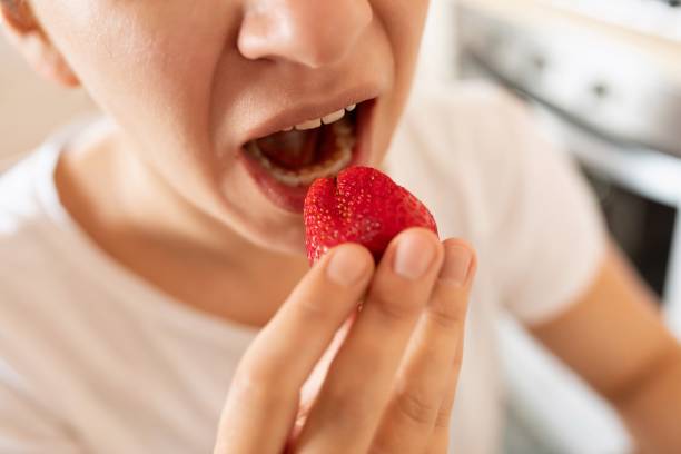 istock woman bites strawberry during snack. proper nutrition 1913242409