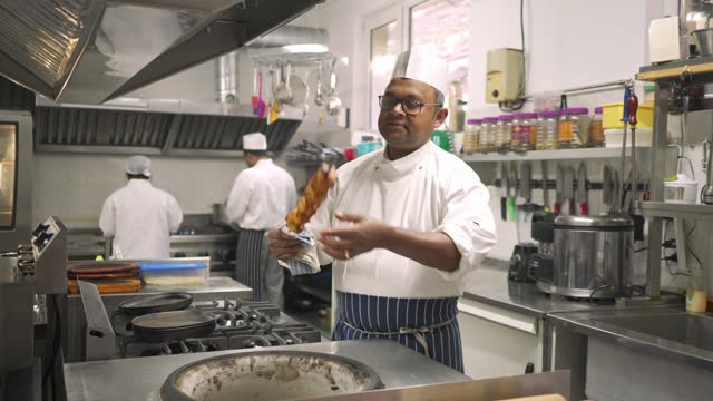 Chef looking at a skewer of cooked chicken