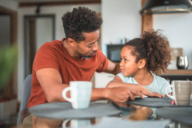 istock Cheerful Black Father Reading A Book With Her Mixed Race Daughter 1913247834