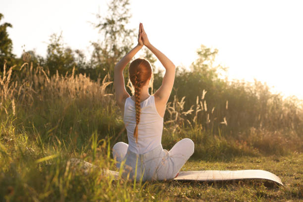 istock Woman practicing Padmasana on yoga mat outdoors on sunny day, back view. Lotus pose 1913258258