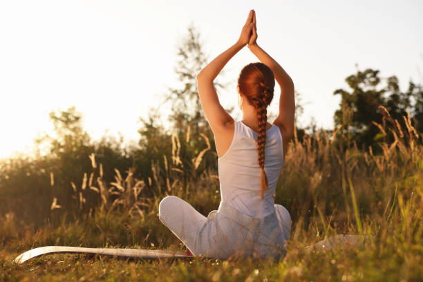 istock Woman practicing Padmasana on yoga mat outdoors on sunny day, back view. Lotus pose 1913260348