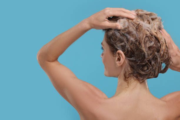 istock Woman washing hair on light blue background, back view 1913286629