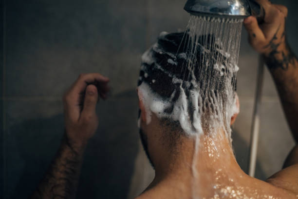 Young handsome man washing hair in the bathroom