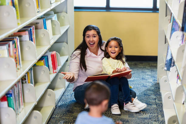istock Mother with young children reading in the library 1913333109