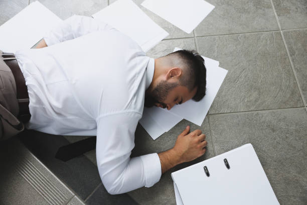 istock Unconscious man with scattered folder and papers lying on floor after falling down stairs indoors, top view 1913333718