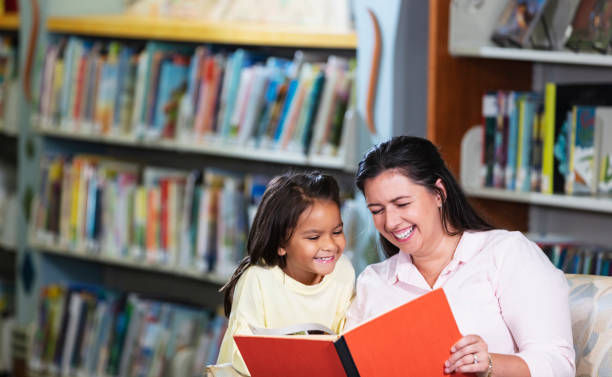 istock Mother and multiracial daughter, reading in library 1913333743