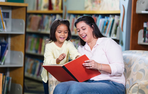 istock Mother and multiracial daughter, reading in library 1913333749