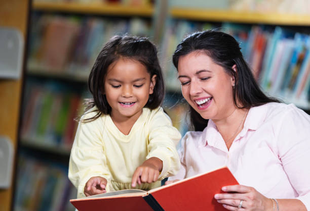 istock Mother and multiracial daughter, reading in library 1913333767