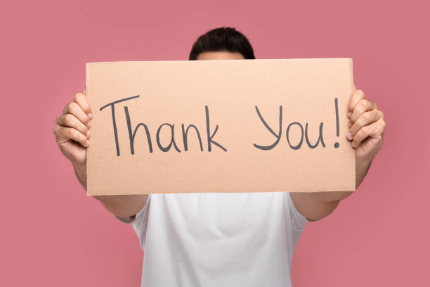 istock Man holding cardboard sheet with phrase Thank You on pink background, selective focus 1913335488