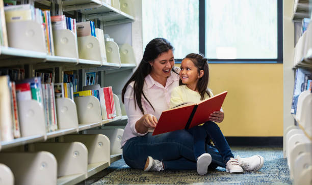 istock Mother, multiracial daughter, reading in library 1913336628
