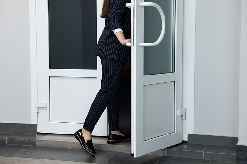 Woman in stylish suit leaving or entering office building, closeup