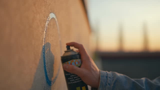 SLO MO Closeup of Hand of Unknown Man Doing Graffiti on Wall with Paint Spray Can at Sunset