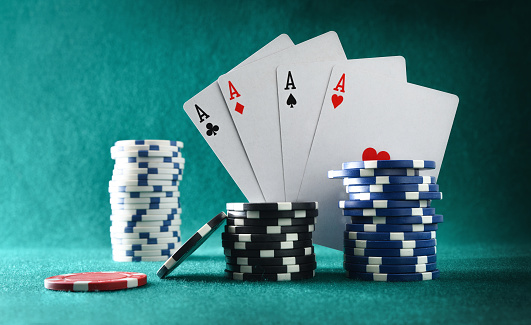 Playing cards showing four aces and chips for betting on a green felt gaming table and same background. Front view.