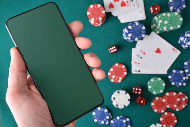 istock Online casino games concept with hand holding mobile and objects 1913355984