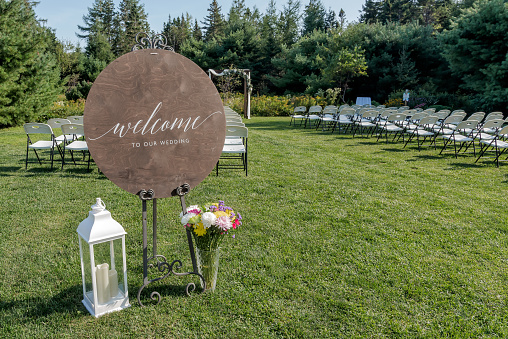 A meadow set up for a wedding ceremony with a welcome to our wedding wooden sign at the entrance.
