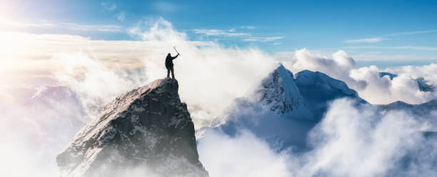istock Adventurous Man Standing on top of Mountain Cliff. Extreme Adventure Composite. 1913376865