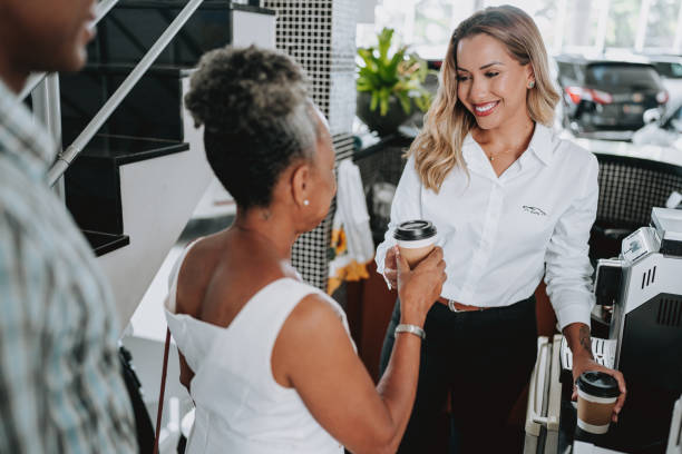 car saleswoman offering coffee to customer - car old african descent car salesperson imagens e fotografias de stock