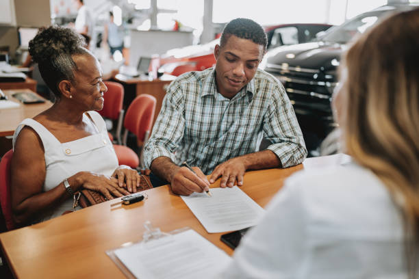 buying a car by signing a contract - car old african descent car salesperson imagens e fotografias de stock
