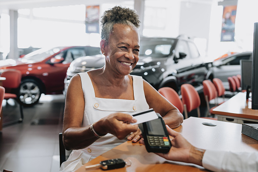 Senior woman buying a car paying with a credit card
