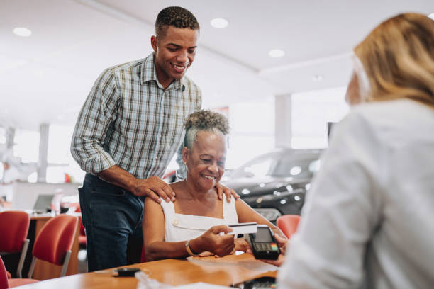 buying a car paying with a credit card - car old african descent car salesperson imagens e fotografias de stock