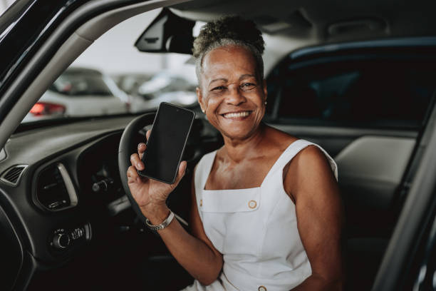 차 안에서 스마트폰을 보여주는 노인 여성 - car old african descent car salesperson 뉴스 사진 이미지