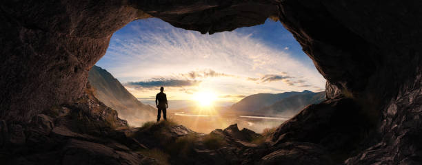 istock Adventurous Man Hiker standing in a cave. River and Mountains in background. Adventure Composite 3d Rendering. 1913384591