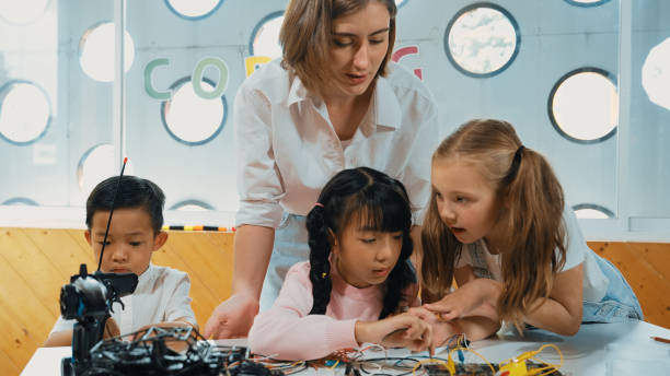 istock Teacher looking at children while diverse student looking at screen. Erudition. 1913389729