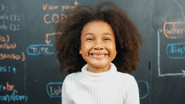 istock Young african girl looking at camera while standing at blackboard. Erudition. 1913428569