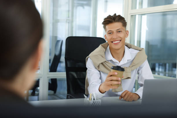 istock Happy man with paper cup of coffee in open plan office 1913457241
