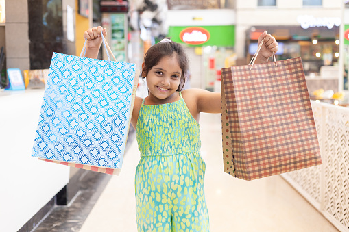 Happy Indian girl in shopping mall with paper bags, shopper bags in hands. Shopping concept