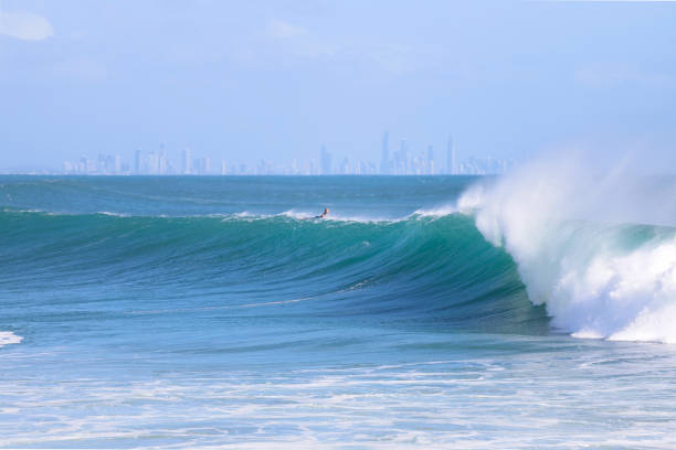 istock Silhouette of a surfer paddling over a wave 1913731772